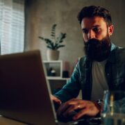 A smart software engineer is sitting in his darkened home office and developing software.