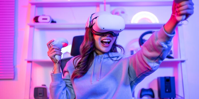 Asian young esport woman gamer use technology VR glasses and play game.